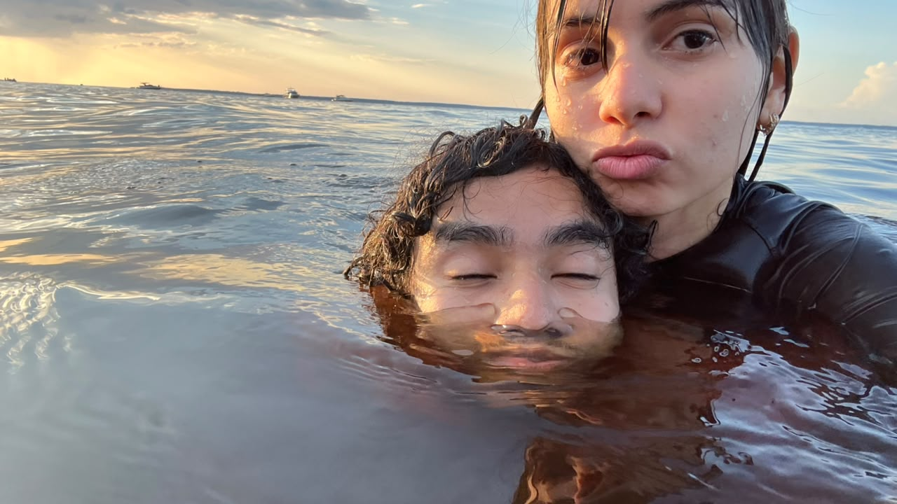 Jennifer e uma pessoa importante juntos na água ao pôr do sol